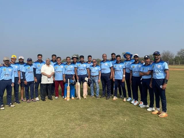 A team in sky-blue kit lined up on a ground with a man in a white shirt among them