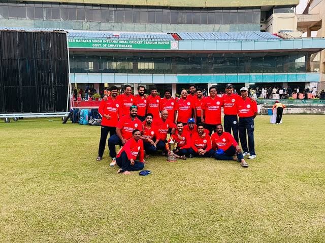 A team in red kit in front of a stadium pavilion