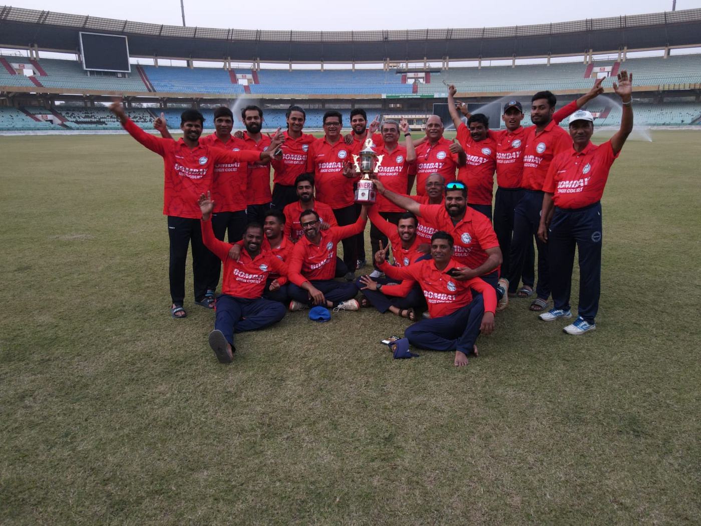 A team in red kit cheering in a stadium, holding a cup
